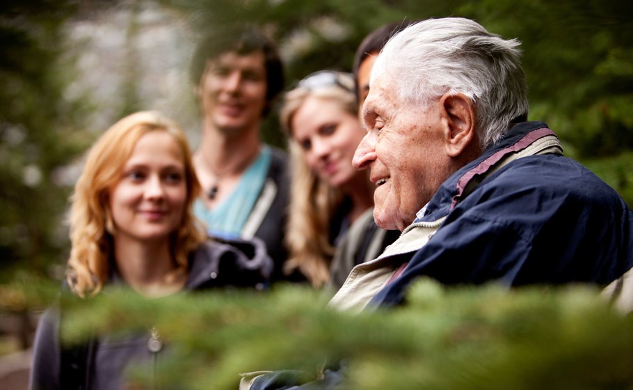 Ältere Person mit Familie draußen.