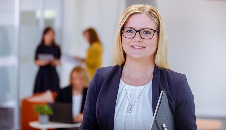 Blonde Frau mit Brille lächelt.