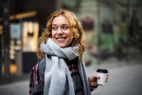 Fröhliche Blondine mit Kaffee zum Mitnehmen.